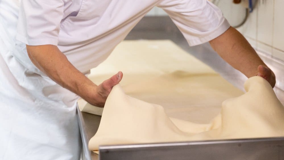Les mains du boulanger qui étirent la pâte